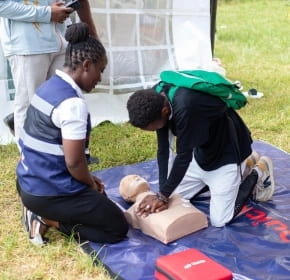 Outdoor CPR practice Trainees practising CPR on a manikin at an outdoor event