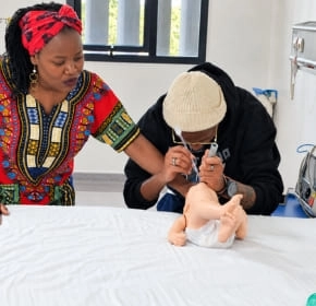 Infant first aid practice Instructor guiding a trainee practising infant first aid on a manikin